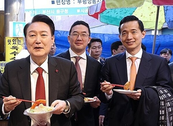 2023년 부산의 한 시장에서 떡볶이를 들고 어색한 미소를 짓고 있는 김동관 부회장(오른쪽). @연합뉴스